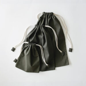 Three dark green drawstring gift bags in different sizes with white cords on a light background